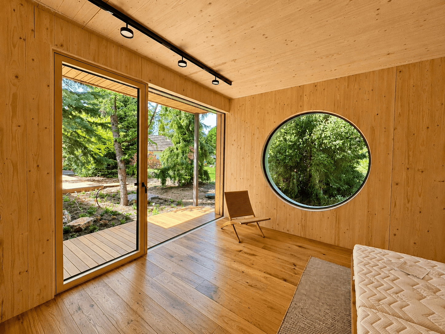 O360 round window in finished timber interior with garden view